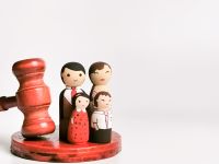 Family law concept. Wooden dolls family with gavel isolated on white background.