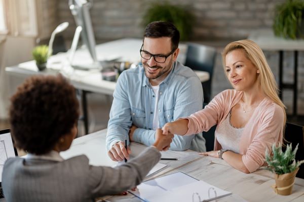 Happy couple handshaking with lawyer while meeting in the office.